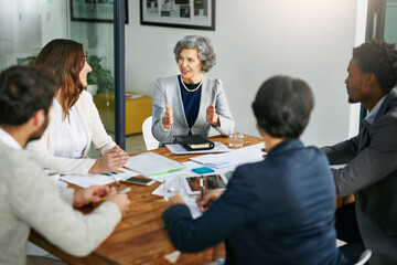 Fototapete - Business people, talking or mature woman in meeting for planning, collaboration or teamwork at office. Group, female mentor or investors with strategy for discussion, conversation or feedback review