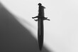 Shadowed dagger, lurking in the depths of darkness, on a solid white background.