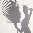 Creative Shadow of Woman with Palm Frond on White Wall