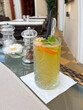 Citrus drink with a straw in a clear glass. Fruity refreshing iced drink spread with decoration on the table.
