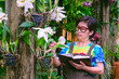 Asian adult woman is taking care of white cattleya orchid plants in her home ornamental garden