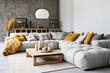 Tufted grey corner sofa against stone cladding wall. Minimalist interior design of modern living room, home.