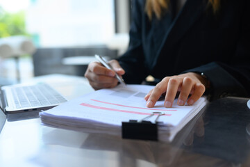 Close up professional businesswoman in suit checking financial reports with charts and graphs