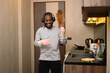 Cheerful man in headphone enjoying domestic chores, cleaning up his house and singing