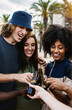 Vertical shot of group of young friends enjoying summertime together. United multiracial people laughing on party while drinking beers at summer vacation