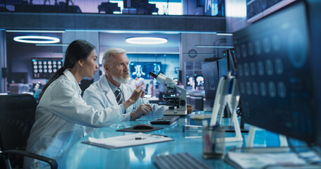 Poster - Biotechnology Medical Research Center: Female Asian Neuroscientist Using Desktop Computer And Talking To Male Caucasian Surgeon With Microscope. Specialists Developing Innovative Cancer Treatment.