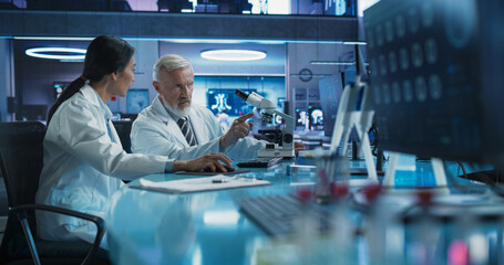 Poster - Biotechnology Medical Research Center: Female Asian Neurologist Using Desktop Computer And Talking To Male Caucasian Scientist With Microscope. Doctors Studying Brain Damage Cases, Finding Solutions.