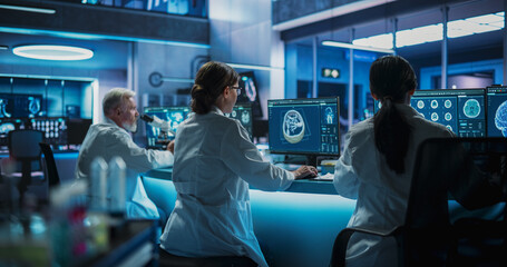 Poster - Back View Of Diverse Scientists Working In Medical Research Center. Male Doctor Using Microscope And His Female Colleagues Looking At CT Brain Scans On Desktop Computers. Biotechnology Lab Concept.