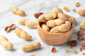 Wall Mural - Peanuts with shell in wooden bowl on white marble table