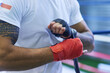 Gym, fighter or man wrapping hands for training, exercising and workout for competition. Professional, boxer and male athlete in ring ready with energy, commitment and boxing with motivation