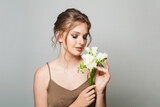 Fototapeta Niebo - Attractive brunette woman with beautiful flowers. Pretty woman with natural makeup and fresh skin
