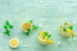 Lemonade with mint. Lemon water drink with ice. Two glasses and lemons on a blue background, shot from above with copy space. Detox beverage. Fresh homemade cocktail