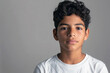 © SOLDATOOFF - Portrait of a young handsome Latino teenager in a white t-shirt against a gray wall.
