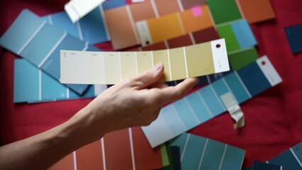 Wall Mural - Closeup of mature womans hands as she looks at paint swatches and considers choosing colors for her home.