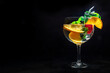 Fancy cocktail with fresh fruit. Gin and tonic drink with ice at a party, on a black background. Alcohol with orange, mint, and strawberry, with a place for text