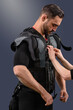 Personal trainer fastening EMS suit on young sporty man, Fitness innovation: Male model with electro muscle stimulator, perfect for showcasing exercise technology