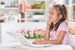 Portrait of little girl sitting at table and using laptop