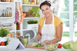 Portrait of beautiful young woman making salad and listening to music