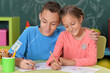 A brother and sister drawing sitting at a table