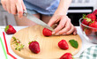 A young woman cuts ripe strawberries with a knife for strawberry lemonade. Close-up. Selective focus.