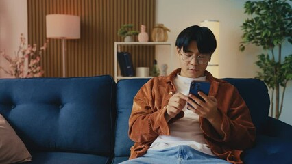 Young Asian man feels unhappy with bad news he got on his phone, disappointment