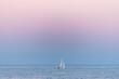 White sailboat at the beautiful blue sea during sunset.