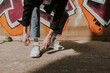 Person tying shoelaces, closeup shot, graffiti wall