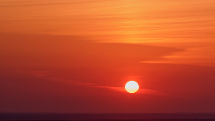 Wall Mural - Red sunset over the horizon with clouds in the sky.