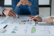 © Tj - close-up hands image, Professional Asian male and female financial consultant or analyst working with them team, brainstorming and analyzing financial data on the report together in the office