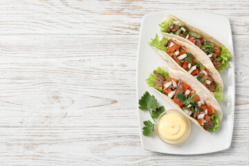Wall Mural - Delicious tacos with meat and vegetables served on wooden table, top view. Space for text