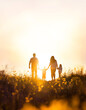 © artpluskr - Silhouette of a happy family walking peacefully along a flower path in a field at sunset, family month loving family background concept, Generative AI