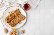 Eastern sweets. Pieces of tasty baklava, walnuts and tea on white tiled table, flat lay. Space for text