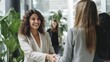 © LukaszDesign - In an office meeting, confident young Hispanic businesswoman shakes hands with coworker. Happy woman celebrating a promotion, transaction, and merger. Creative startup agency coworkers