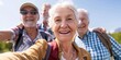 © LukaszDesign - A group of energetic elders taking a selfie or video call on a sunny day with a mountain view. Outdoor exercise for happy retirees. Active, healthy living
