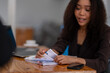 © Wasana - Engaged African American businesswoman sorting through business documents at her desk with a laptop nearby.