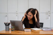 © Wasana - Cheerful African American businesswoman having a phone conversation while working on a laptop in a modern office.