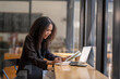 © Wasana - Engaged African American businesswoman working on her laptop while sitting in a sunny café setting.