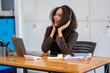 © Wasana - Happy African American businesswoman listening to music with headphones while working on a laptop in her office.