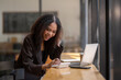 © Wasana - Engaged African American businesswoman working on her laptop while sitting in a sunny café setting.