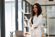 © Wasana - Young African American businesswoman stands confidently in a stylish office environment, portraying professionalism and success.