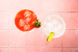 Fototapeta  - Margarita cocktails. Classic and strawberry margarita with tequila, ice and lime at color background. Top view on pink tile.