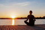 Fototapeta Natura - mindfulness, silhouette of woman meditating near the lake, conscious yoga and meditation