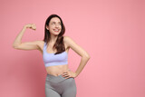 Fototapeta Koty - Happy young woman with slim body showing her muscles on pink background, space for text