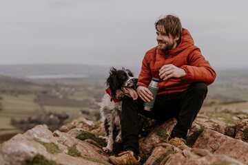 Man sitting with dog on mountain photo