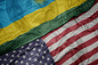 waving colorful flag of united states of america and national flag of rwanda on the dollar money background. finance concept.