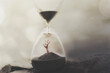 hand emerging from the sand inside an hourglass, concept of time