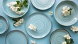 a creatively arranged top view of various light blue ceramic plates and bowls with subtle white flower decorations flat lay top view creative color design concept