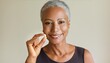 © Marko - Closeup portrait of happy middle aged 50s woman holding pill taking dietary supplements. Portrait of smiling adult attractive woman taking collagen vitamins health in menopause