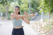 Sport woman warming up by stretching her shoulder in a park