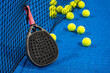 several balls by the net on a blue paddle tennis court